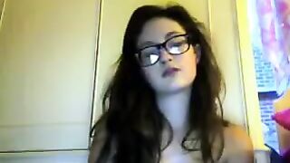 A cute girl in glasses undresses during a video chat with someone