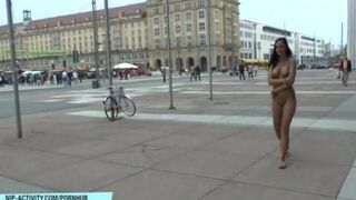 A naked chick is walking on the city streets and showing her body