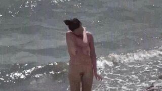 Nudist couple have fun on the beach and show affection