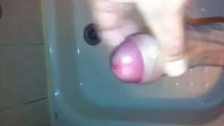The kid caresses his dick with his hand in the shower stream
