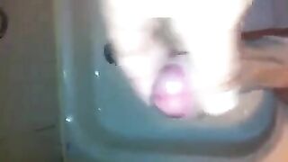 The kid caresses his dick with his hand in the shower stream