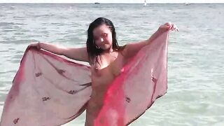 A hot girl is bathing in the sea naked, her body glistening under the sun