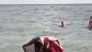 A hot girl is bathing in the sea naked, her body glistening under the sun