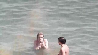 A group of naked girls playing in the sea and getting wet