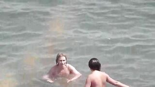 A group of naked girls playing in the sea and getting wet