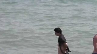 A group of naked girls playing in the sea and getting wet