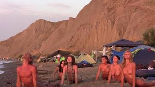 A group of naked people play volleyball on the beach