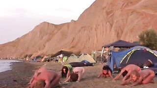 A group of naked people play volleyball on the beach